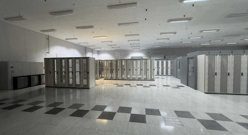 Spacious server room with rows of racks and bright ceiling lights.